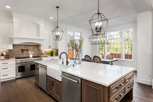White farmhouse kitchen with large island, pendant lanterns, and natural light