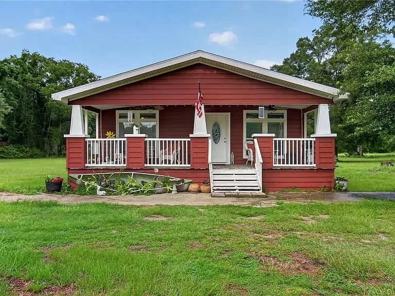 Red-sided country home with covered wraparound porch on a 5-acre North Florida property